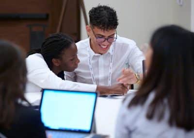 Two people sit and collaborate at a table, reviewing Submission Guidelines. A laptop rests in the foreground, aiding their focused discussion.