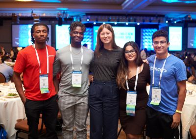 Five people standing together indoors at a conference, wearing name tags and casual clothing.